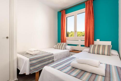 a room with two beds and a window at Apartamentos Alta Galdana in Cala Galdana