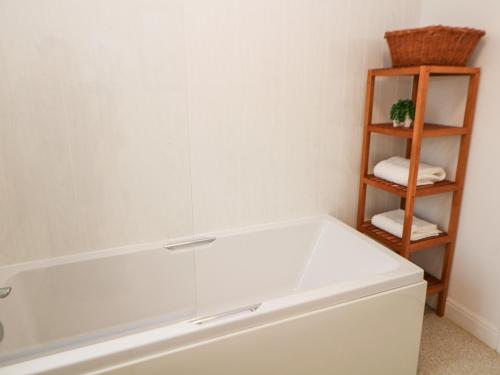 uma casa de banho com banheira e uma prateleira com toalhas em Lower Cowden Farm em Bakewell