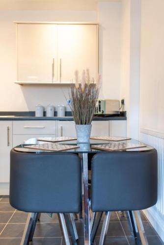 a dining room table with two chairs and a vase on it at No 21 in Mansfield