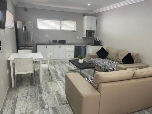 ein Wohnzimmer mit einem Sofa und einem Tisch sowie eine Küche in der Unterkunft Guest house on Gillian Unit 7 in Ballito