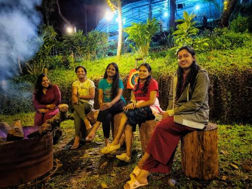 a group of women sitting on wooden benches at Spies Munnar Camping in Chinnakanal