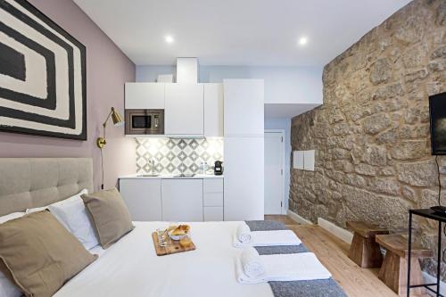 een slaapkamer met een wit bed en een stenen muur bij Cimo de Vila 62 by LovelyStay in Porto