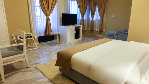 1 dormitorio con 1 cama blanca grande y TV en Sunset Inn en Monrovia