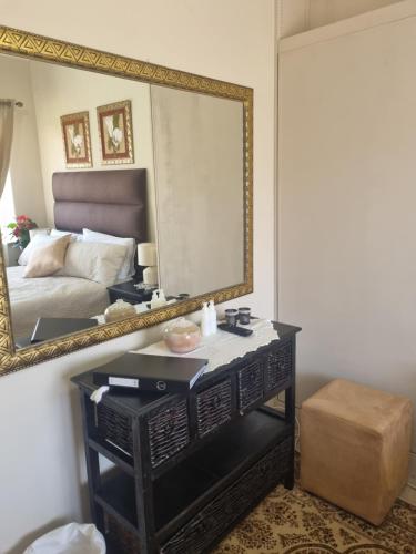 a bedroom with a mirror and a table with a bed at Isabel's B & B in Krugersdorp