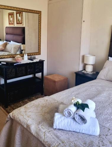 a bedroom with a bed with towels and a mirror at Isabel's B & B in Krugersdorp