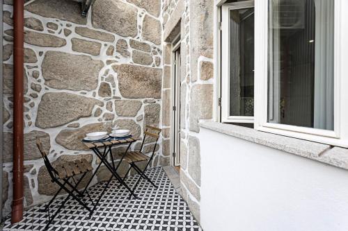 een patio met een tafel en stoelen naast een stenen muur bij Cimo de Vila 62 by LovelyStay in Porto