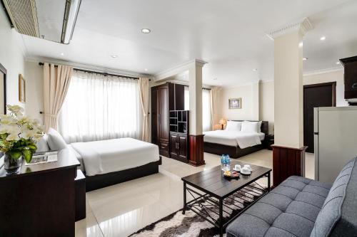a hotel room with two beds and a couch at La Bonita Hotel and Apartments in Ho Chi Minh City