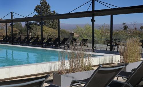 a swimming pool with chairs and a table at Pinares Panorama Suites & Spa in Villa Carlos Paz
