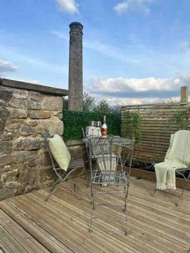 a patio with a table and chairs on a wooden deck at Sunny Luxurious 2 bedroom Holiday cottage in Embsay
