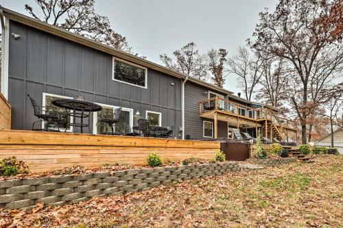 a gray house with a deck and a patio at Lakefront Rogers Getaway with Hot Tub and Deck! in Rogers