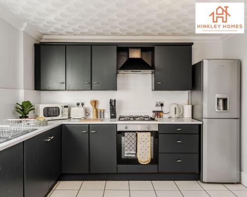 a kitchen with black cabinets and white appliances at Spacious 3 bedroom house with wifi and car parking By Hinkley Homes Short Lets & Serviced Accommodation in Waterloo