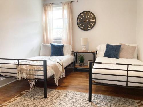 a bedroom with two beds and a clock on the wall at The Rustic Retreat- close to downtown in Bristol