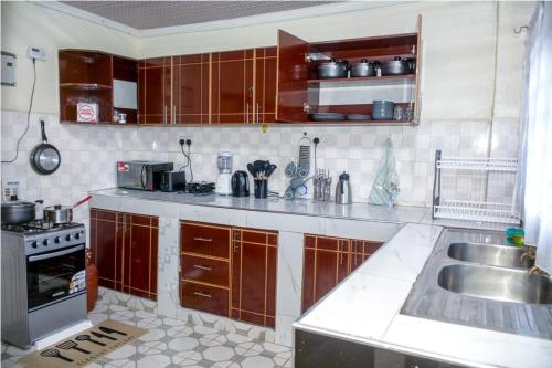 a kitchen with wooden cabinets and a sink at Exquisite 2BR Ensuite Apartment close to Rupa Mall, Mediheal Hospital, and St Lukes Hospital in Eldoret