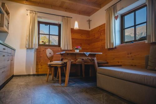- un salon avec une table, un canapé et des fenêtres dans l'établissement Brünnl's Försterhütte, à Parcines