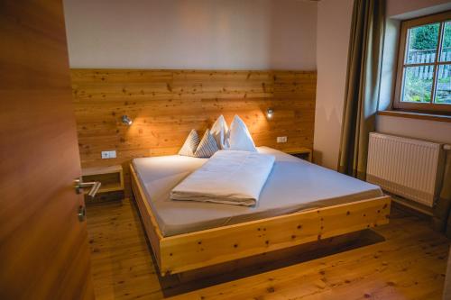 1 dormitorio con 1 cama con pared de madera en Brünnl's Försterhütte en Parcines