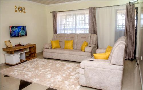 a living room with a couch and yellow pillows at Exquisite 2BR Ensuite Apartment close to Rupa Mall, Mediheal Hospital, and St Lukes Hospital in Eldoret