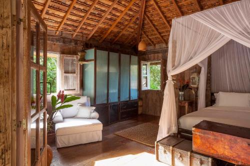 Un dormitorio con una cama y una silla y ventanas. en UXUA Alma, en Trancoso