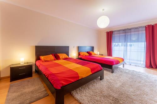um quarto com 2 camas e uma janela com cortinas vermelhas em Apartamento T3 Beira Mar na Nazaré