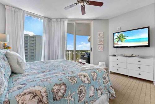 a bedroom with a bed and a flat screen tv at Pink Sunsets at the Palms of Destin Across from Beach, Heated Pool Shuttle & Dining in Destin