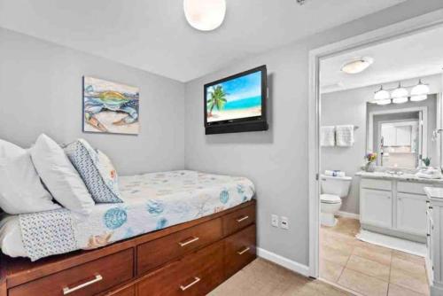 a bedroom with a bed and a bathroom with a sink at Pink Sunsets at the Palms of Destin Across from Beach, Heated Pool Shuttle & Dining in Destin