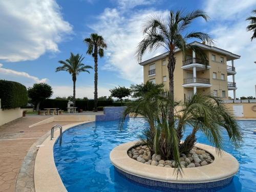 a swimming pool with palm trees in front of a building at Apartamento Panoramica Golf in San Jorge