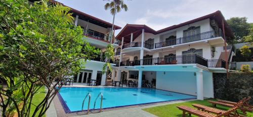 an exterior view of a hotel with a swimming pool at Chill Hill Hikkaduwa in Hikkaduwa