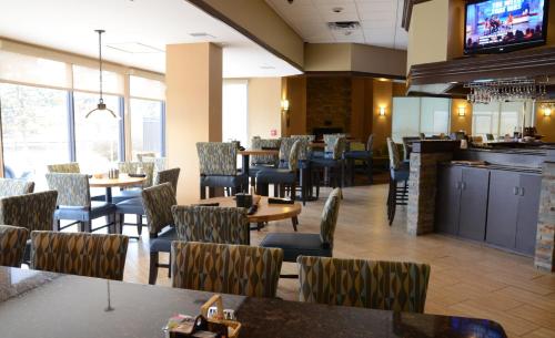 a restaurant with tables and chairs and a tv at Holiday Inn Staunton Conference Center by IHG in Staunton