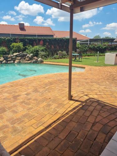 a patio with an umbrella and a swimming pool at Isabel's B & B in Krugersdorp