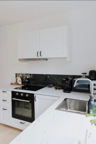 a kitchen with white cabinets and a stove and a sink at Au Numéro 5 in Tilff