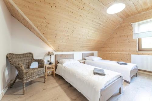 a attic bedroom with two beds and a chair at Cicho-sza! in Solina