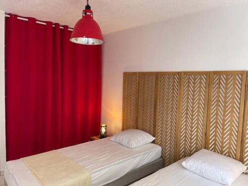una camera con due letti e una tenda rossa di T3 de Standing aux trois ilets / Vue Mer a Les Trois-Îlets