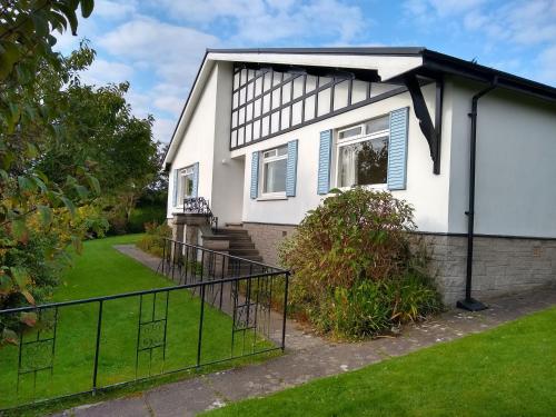 a white house with blue shutters on it at Silverdale Mount in Grange Over Sands