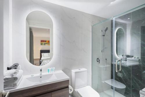 a bathroom with a sink and a shower with a mirror at Nexus Townhouse with Parking and Wi-Fi in Auckland