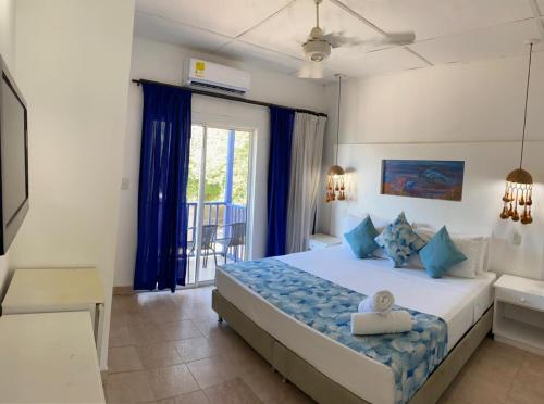 1 dormitorio con 1 cama grande con almohadas azules en La Ballena Azul Hotel, en Taganga