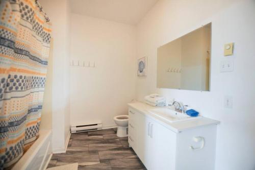 a white bathroom with a toilet and a sink at Le 1808 - Spacieux avec Balcon - Nord de Québec in Quebec City