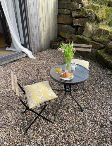 a table and two chairs and a vase of flowers on a patio at Rossendale Holiday Cottages & Spa in Rossendale