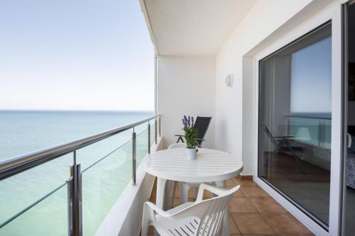 a balcony with a white table and chairs and the ocean at Spectacular Sea Views Torremolinos in Torremolinos