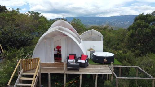 a large white dome tent with a deck and chairs at Origen Glamping en Villa de Leyva in Villa de Leyva