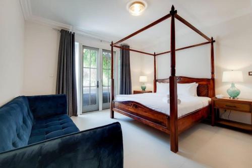 a bedroom with a four poster bed and a couch at Whispering Pines, JGE - Vacationer in Dubai