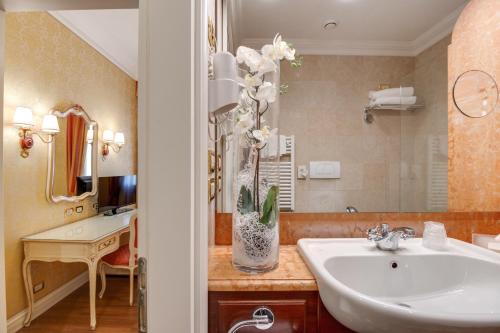 a bathroom with a sink and a vase of flowers at Hotel Antiche Figure in Venice