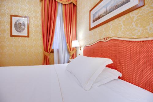 a bedroom with a white bed and a red headboard at Hotel Antiche Figure in Venice
