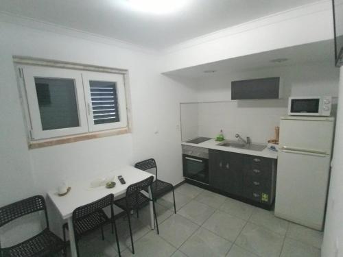 La cuisine est équipée d'une table, de chaises et d'un réfrigérateur blanc. dans l'établissement Ginjals-67, à Almargem do Bispo