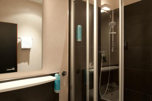 a bathroom with a glass shower with a mirror at Hotel Topas Frankfurt City in Frankfurt/Main