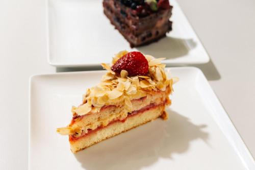 a piece of cake with a strawberry on a plate at Hotel Čad in Ljubljana