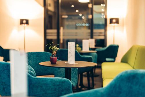a cafe with green chairs and a table with a plant on it at Aktivhotel Wildschütz in Gmunden