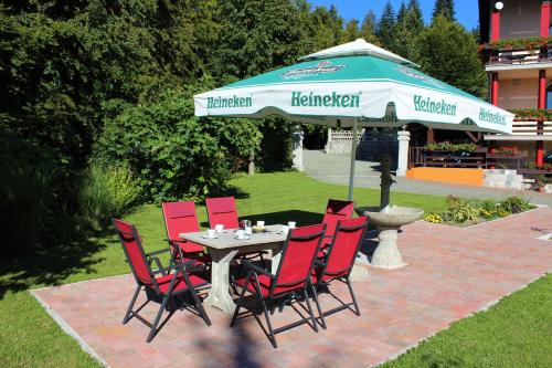 a patio table with red chairs and an umbrella at Apartment & Studio Forest Paradise in Cerkno