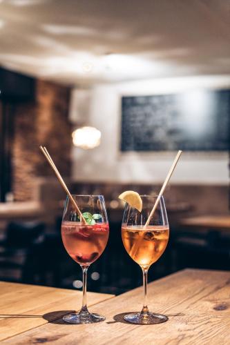 two glasses of wine sitting on a wooden table at Aktivhotel Wildschütz in Gmunden