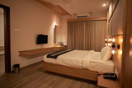 Habitación de hotel con cama y TV en HILUX COURTYARD, en Palakkad