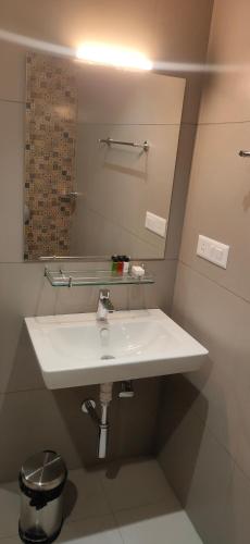 a bathroom with a white sink and a mirror at HILUX COURTYARD in Palakkad