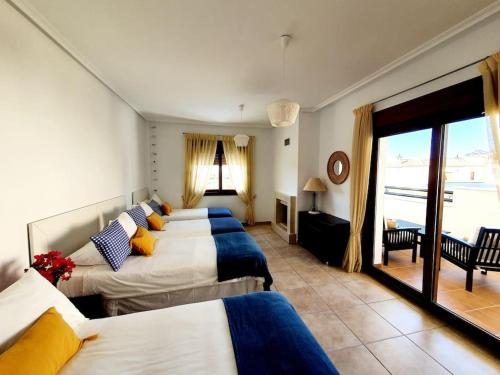 a hotel room with four beds and a balcony at Espectacular Villa PISCINA PRIVADA Altaona GOLF in Murcia